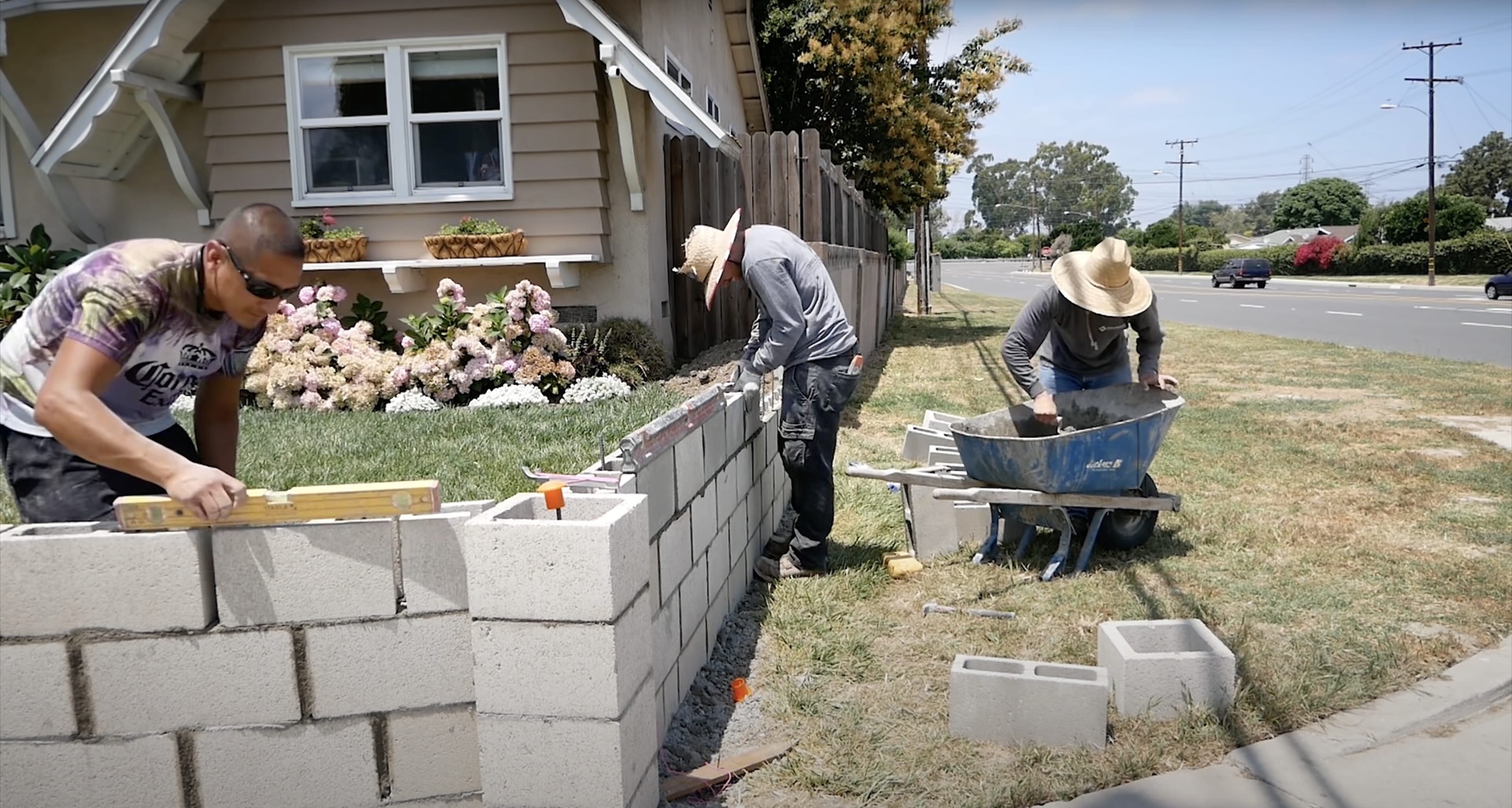 Concrete block retaining wall construction by experienced concrete contractors Professional concrete workers building concrete block retaining wall in residential yard in Waterbury Connecticut